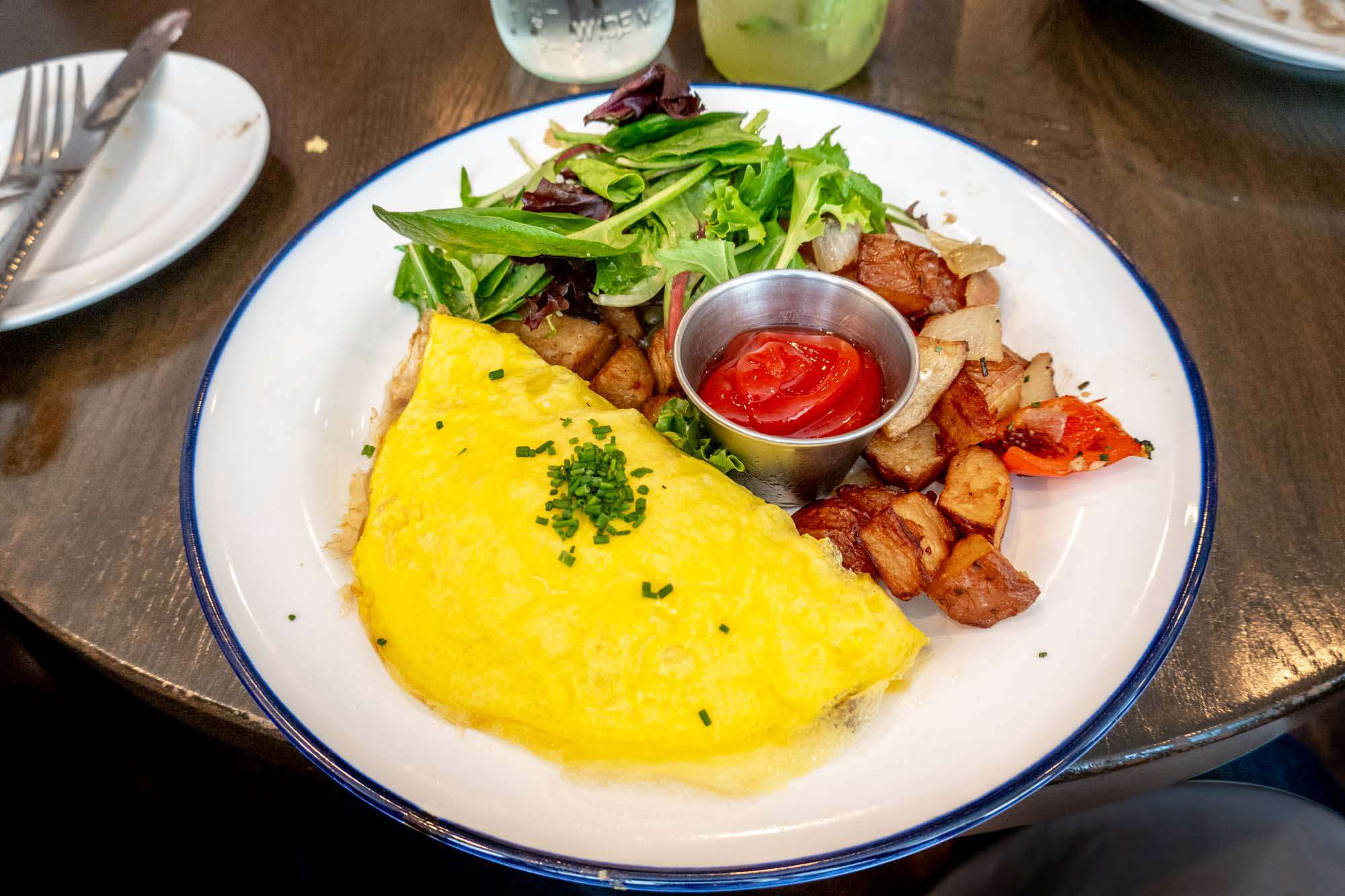 Omelet, potatoes, and a salad on a plate.