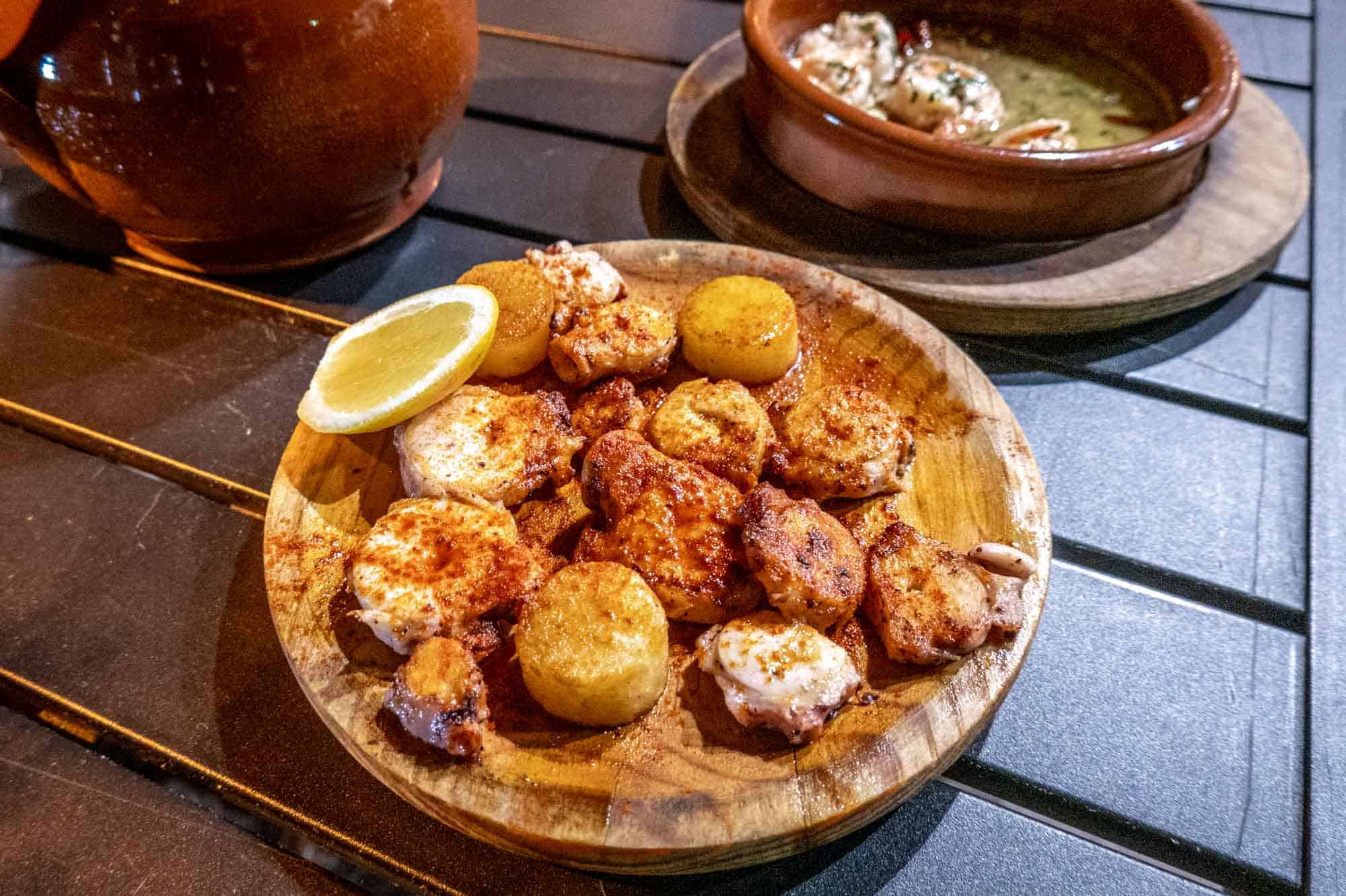 Medallions of octopus and potato on wood plate